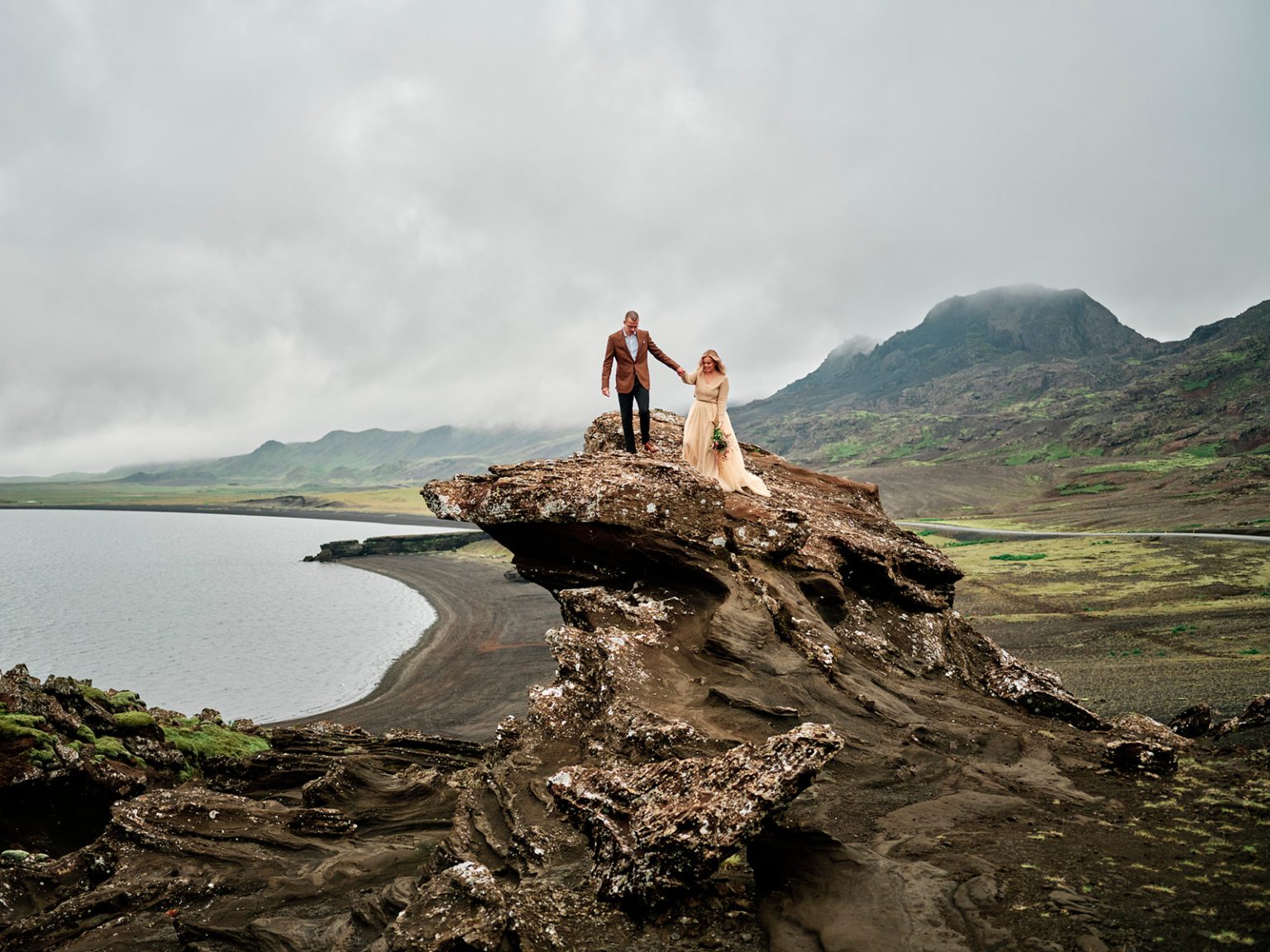 Kim and Daniel on a mossy cliff above the sea, a Reykjanes engagement