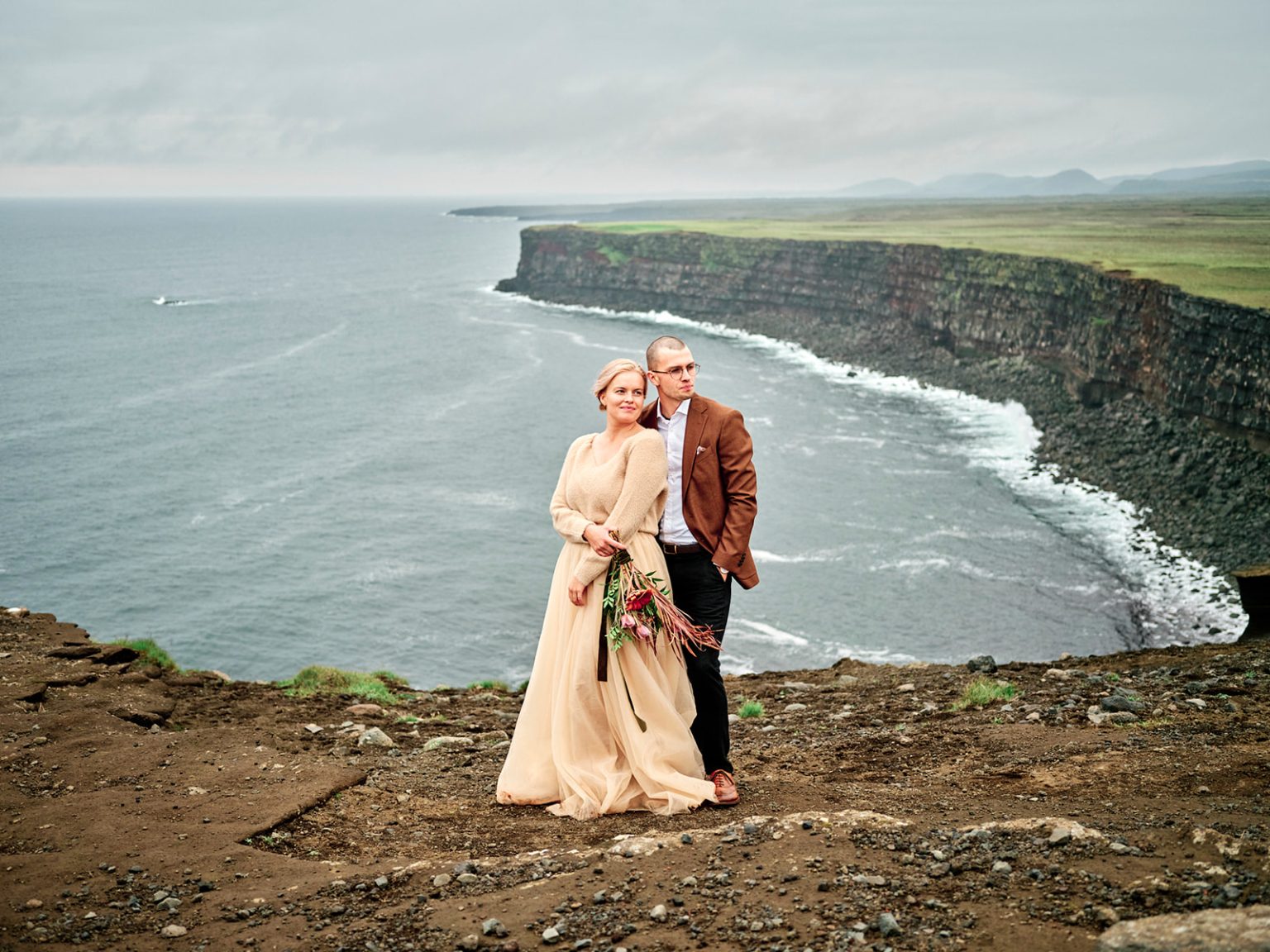 The couple on the green sea cliffs of Reykjanes, Iceland