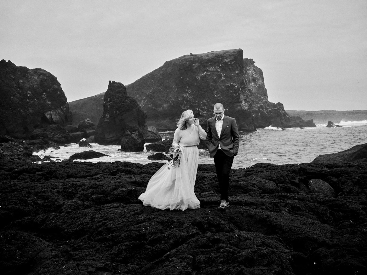 The couple in a lava sea arch, black and white, Reykjanes