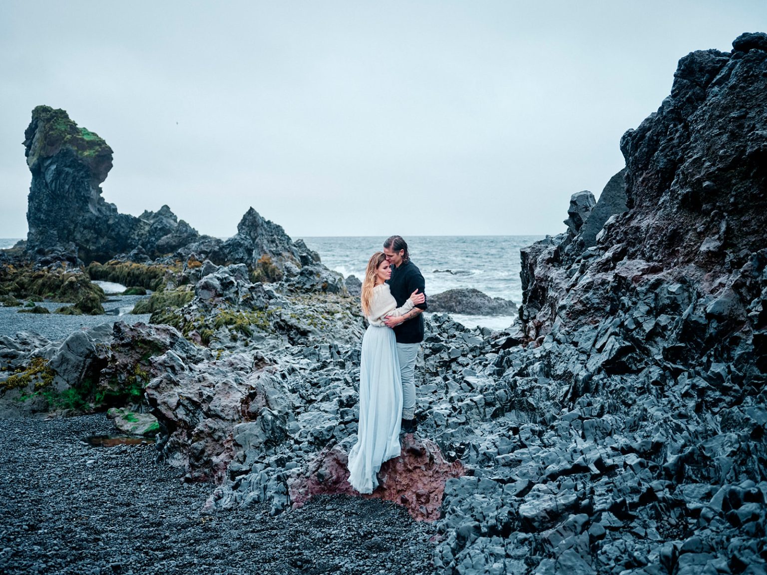 The couple on a black-sand beach below the sea stacks, Snæfellsnes elopement
