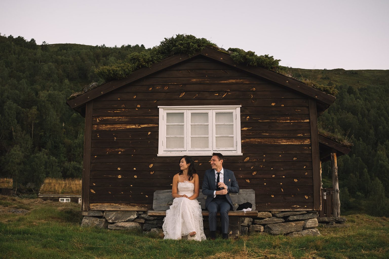 The couple by an old cabin above the fjord at sunrise, Juvet, Norway