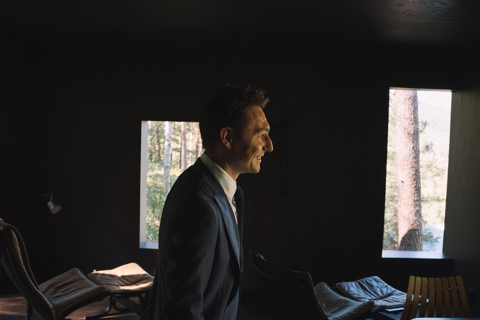 The groom in a glass cabin looking out at Juvet, Norway wedding