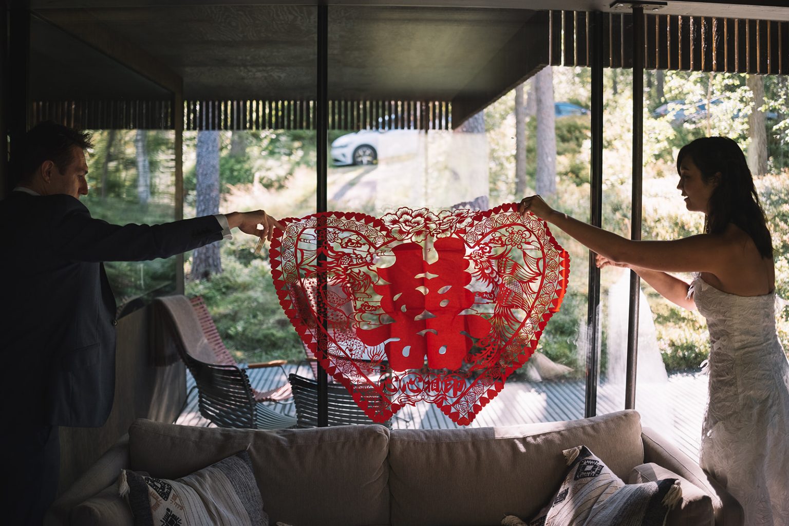 Ida and James with a red double-happiness banner in a glass cabin, Juvet