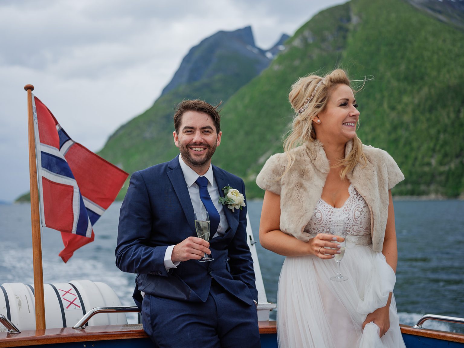 Bride and groom on the boat with the Sunnmøre peaks behind, Hotel Union Øye elopement