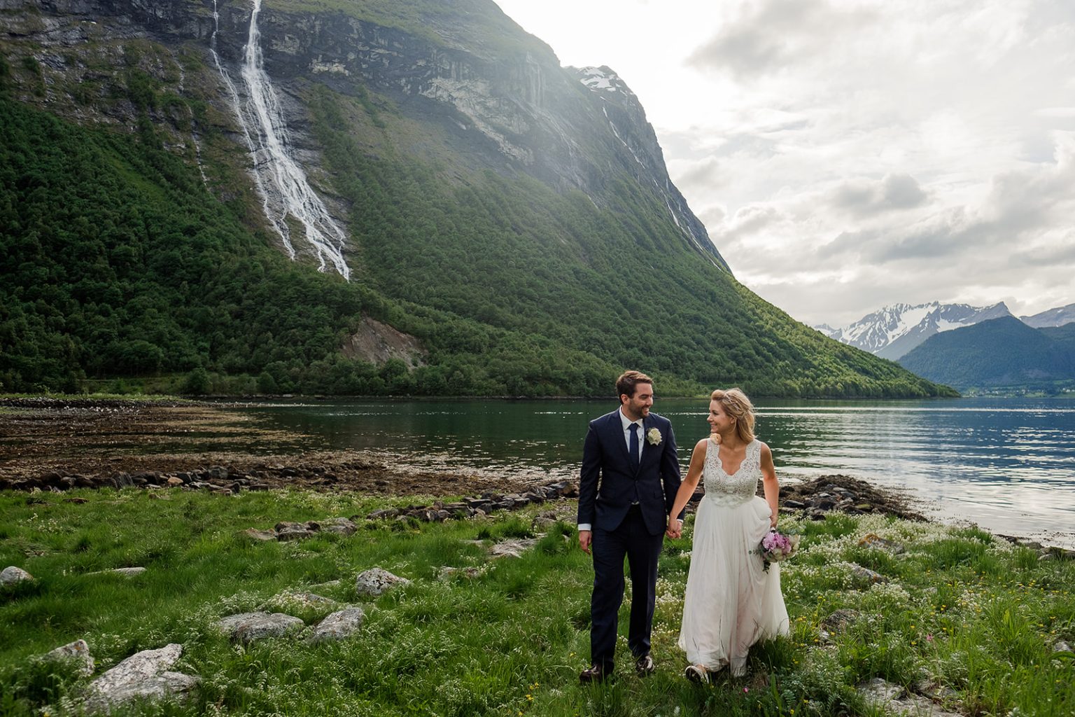 Bride and groom dwarfed by a waterfall at Øye