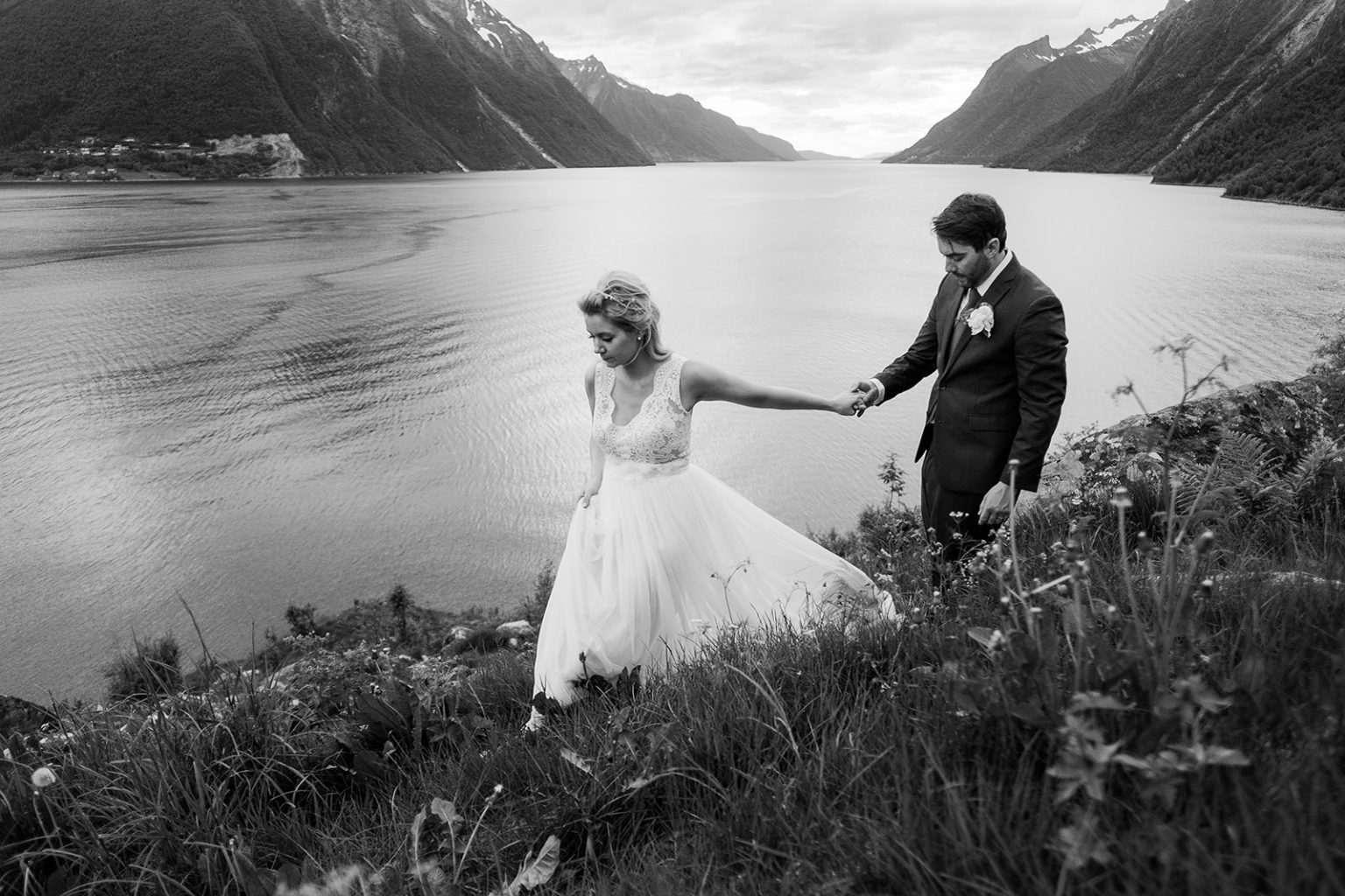 Bride and groom on the hillside above the fjord