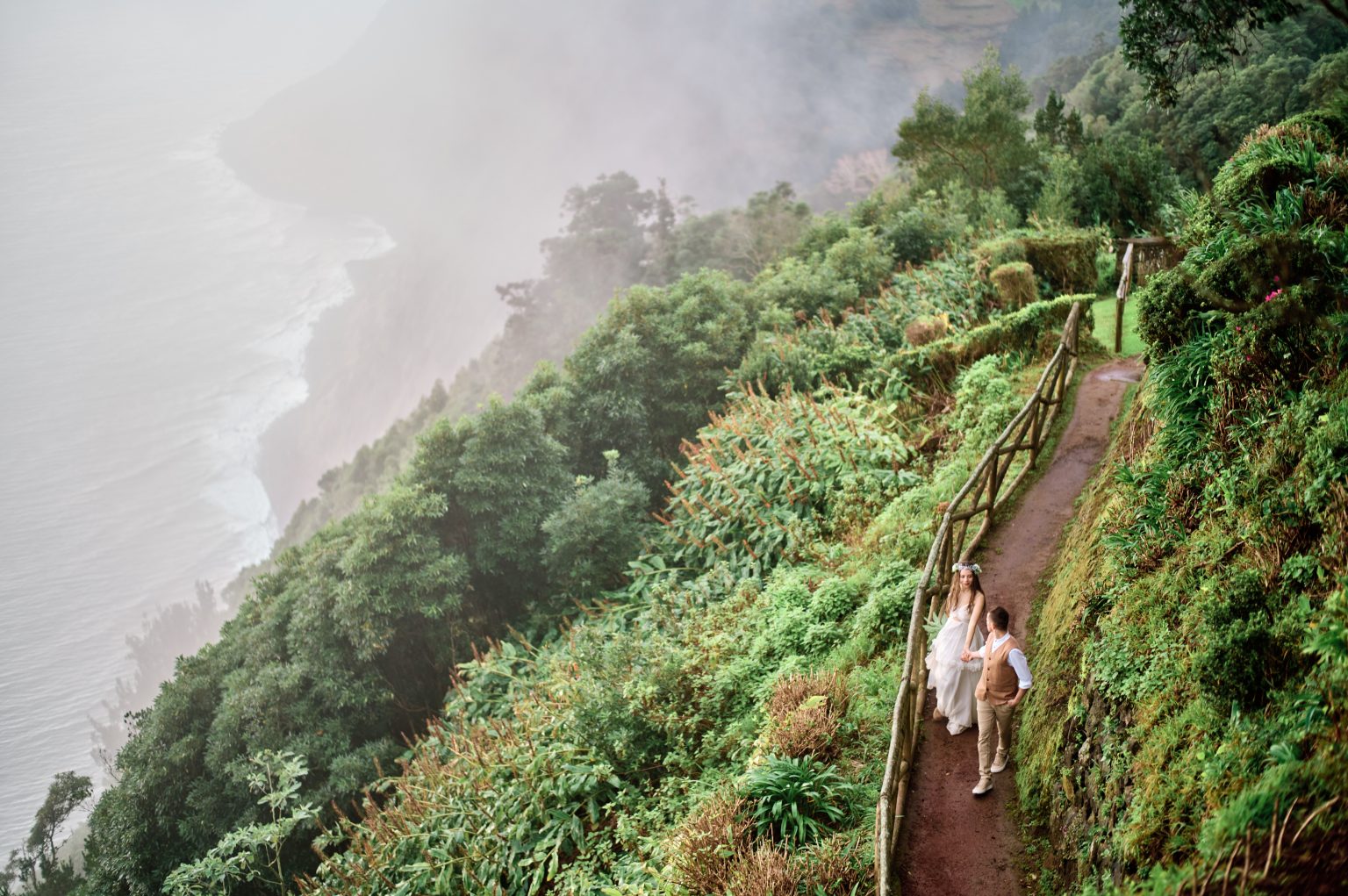 A garden path winding down a green ridge to the sea, São Miguel