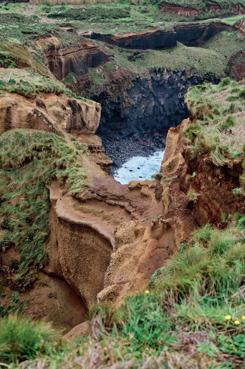 Rust-red cliffs dropping to the sea, São Miguel