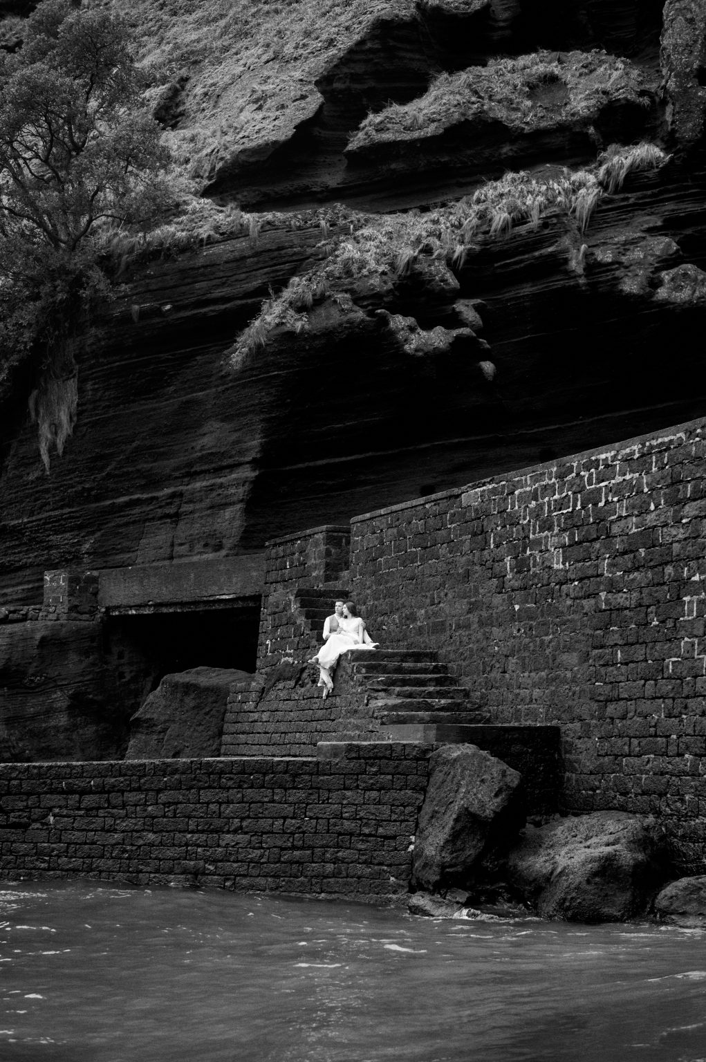 The bride at a stone harbour on São Miguel, black and white