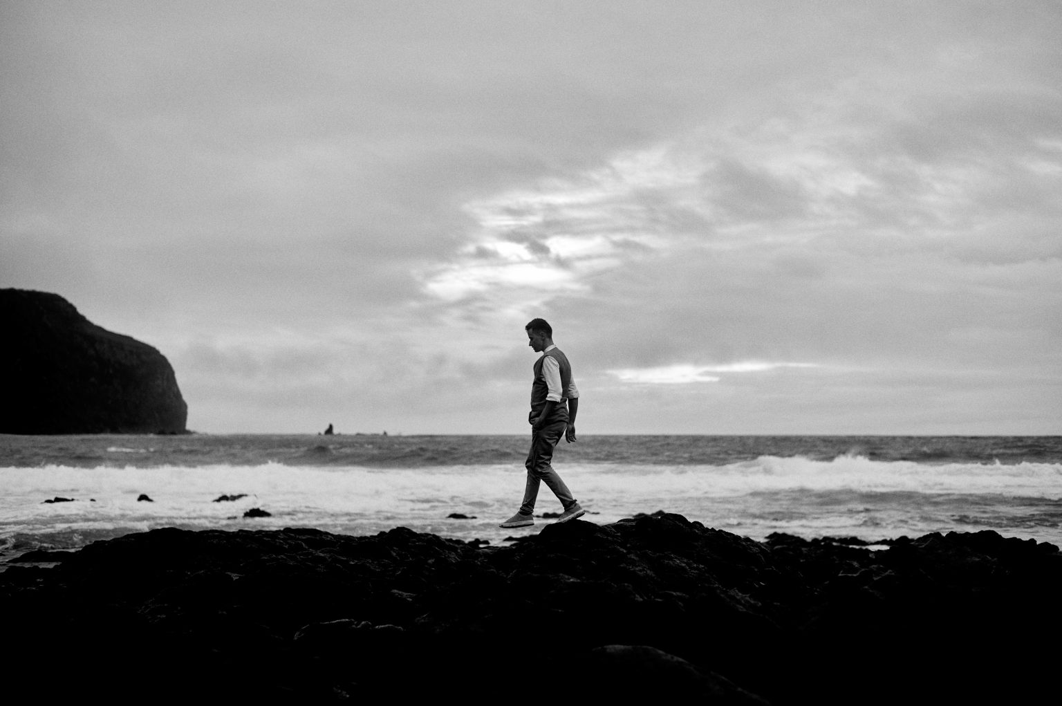 The groom walking the black beach at Mosteiros