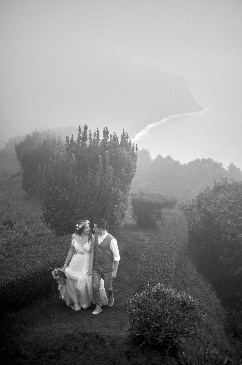Silvia and Florin small on a misty green cliff, São Miguel