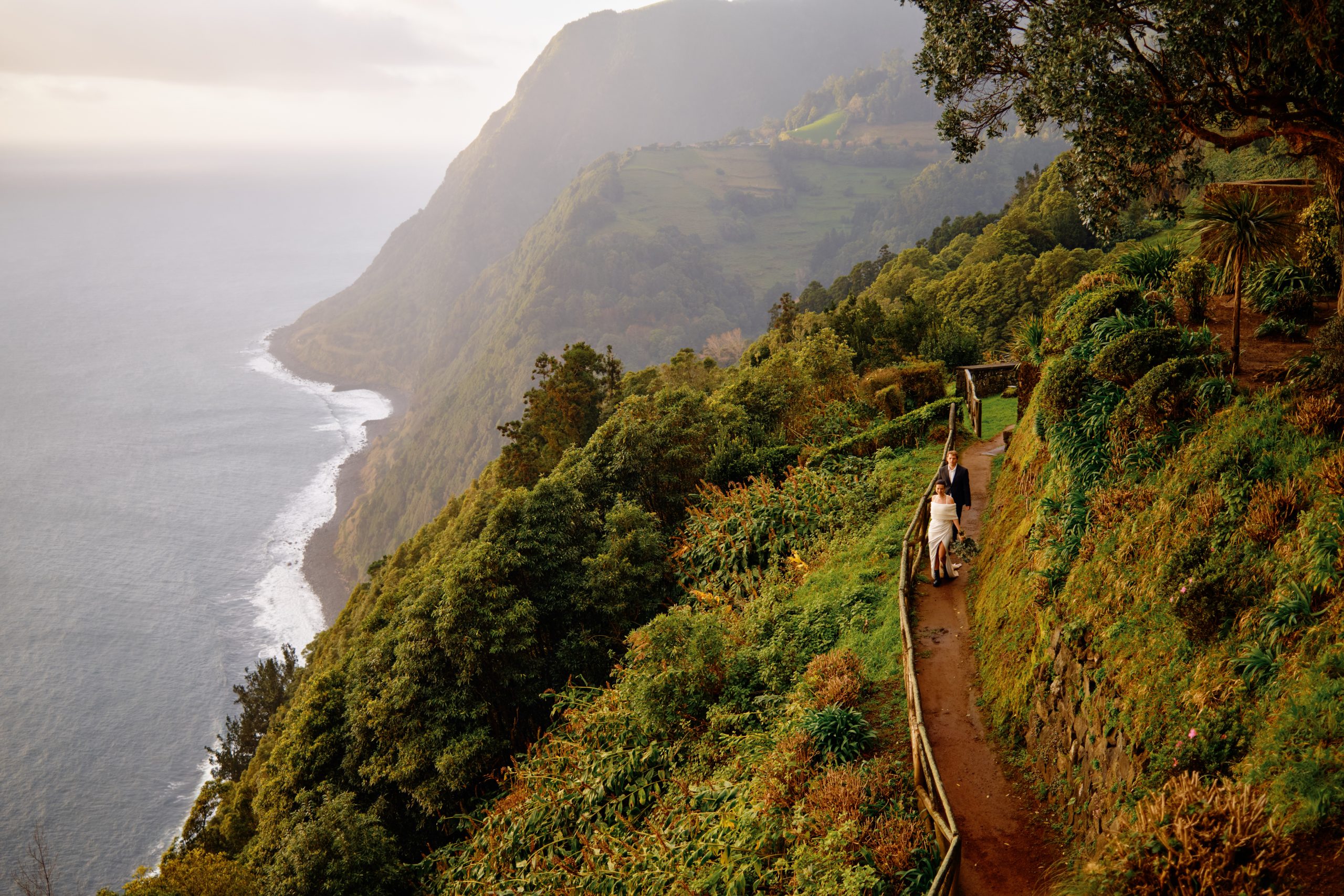 A couple on a green cliff path high above the Atlantic on São Miguel