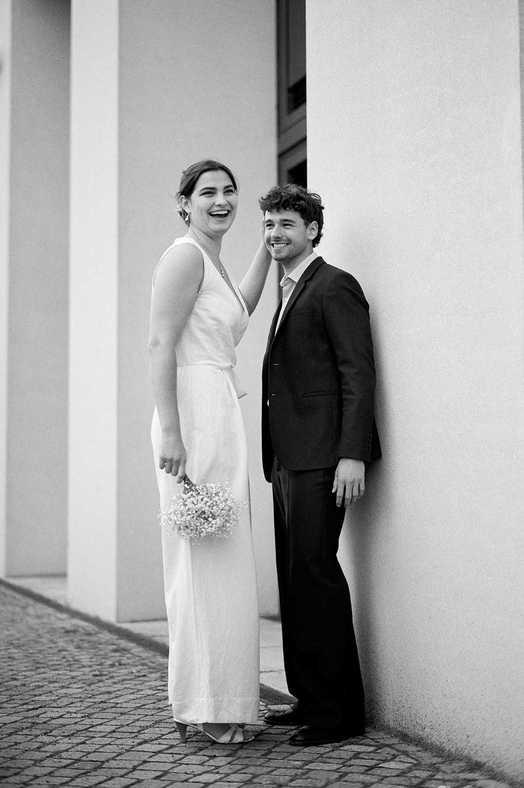 Black and white Berlin engagement portrait of a couple against a white wall - Nordica Photography