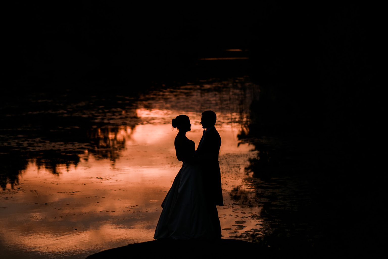Bride and groom at sunset by the water