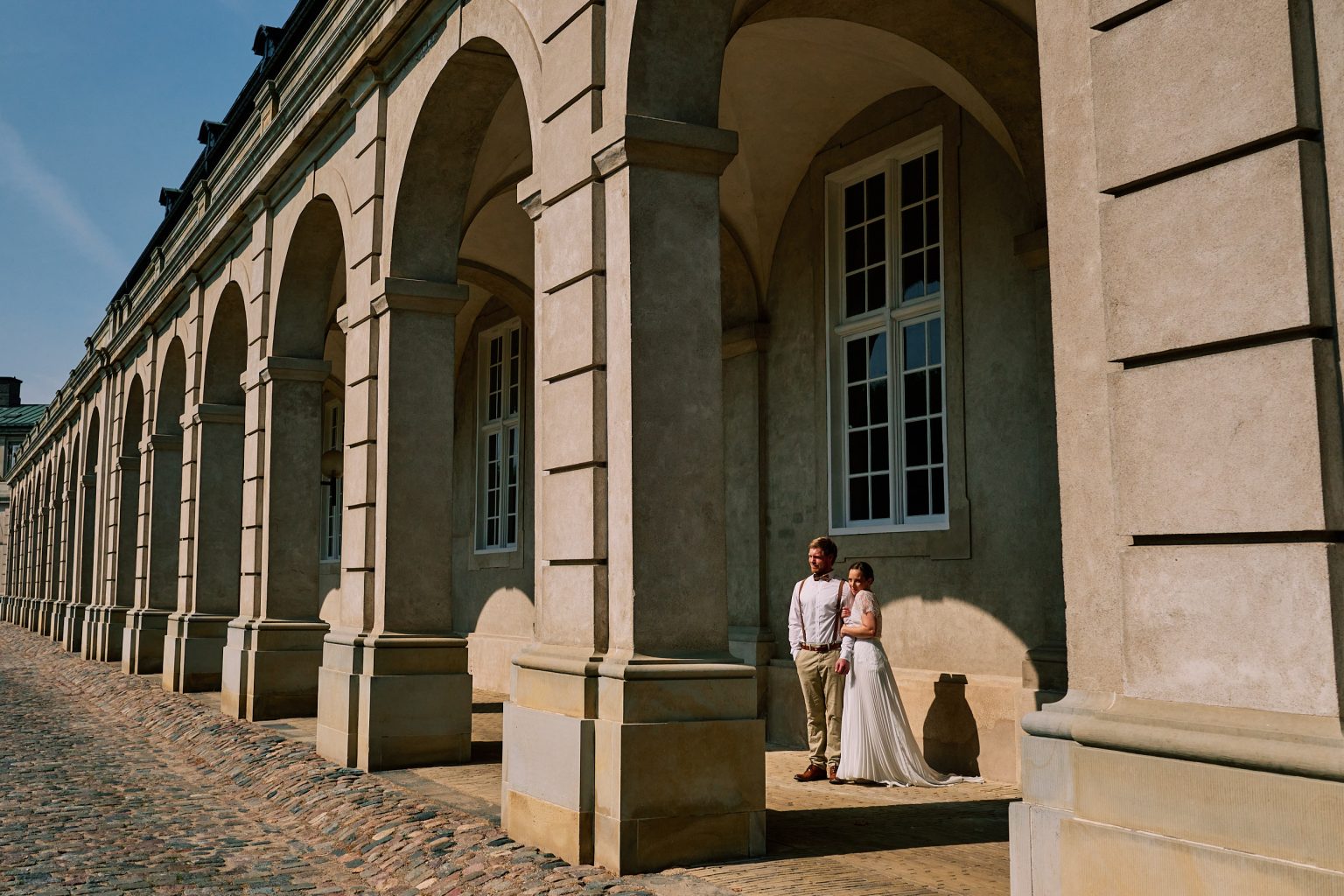 Couple beneath a grand stone arcade in Copenhagen
