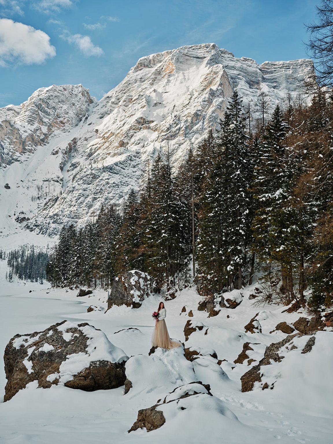 Two figures on the frozen lake beneath the mountains, Dolomites winter elopement