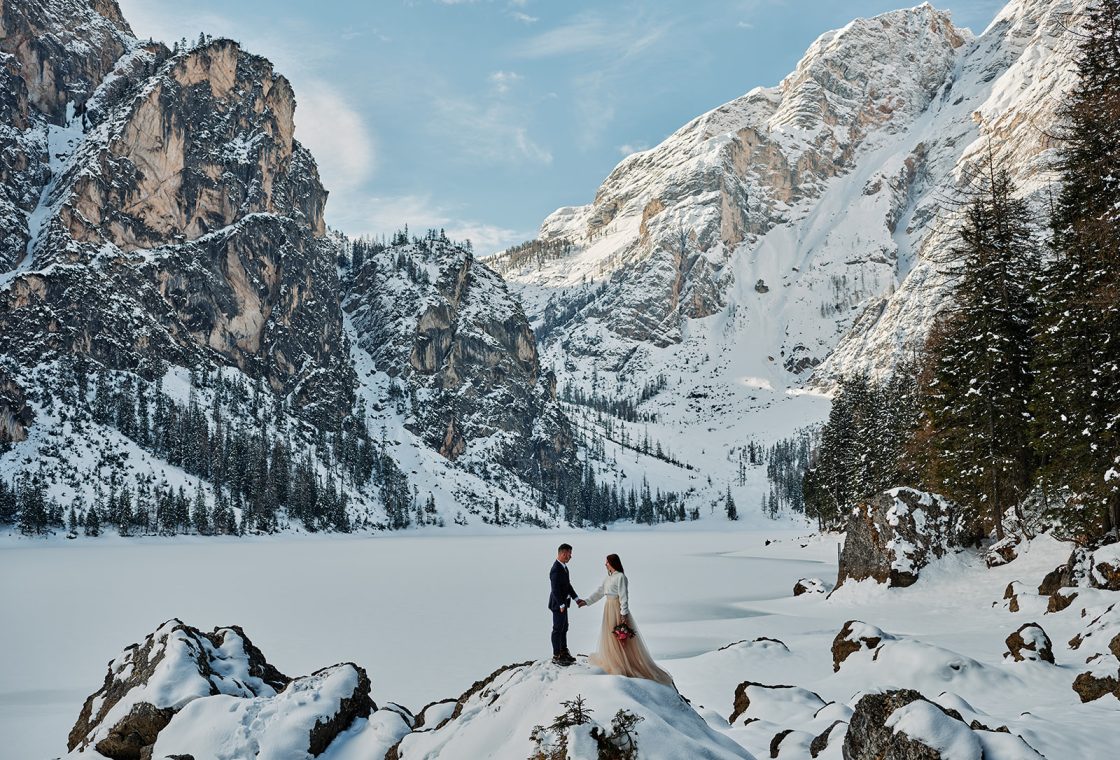 Kristina and Cristian embracing below the snowy Dolomite peaks, a Dolomites winter elopement