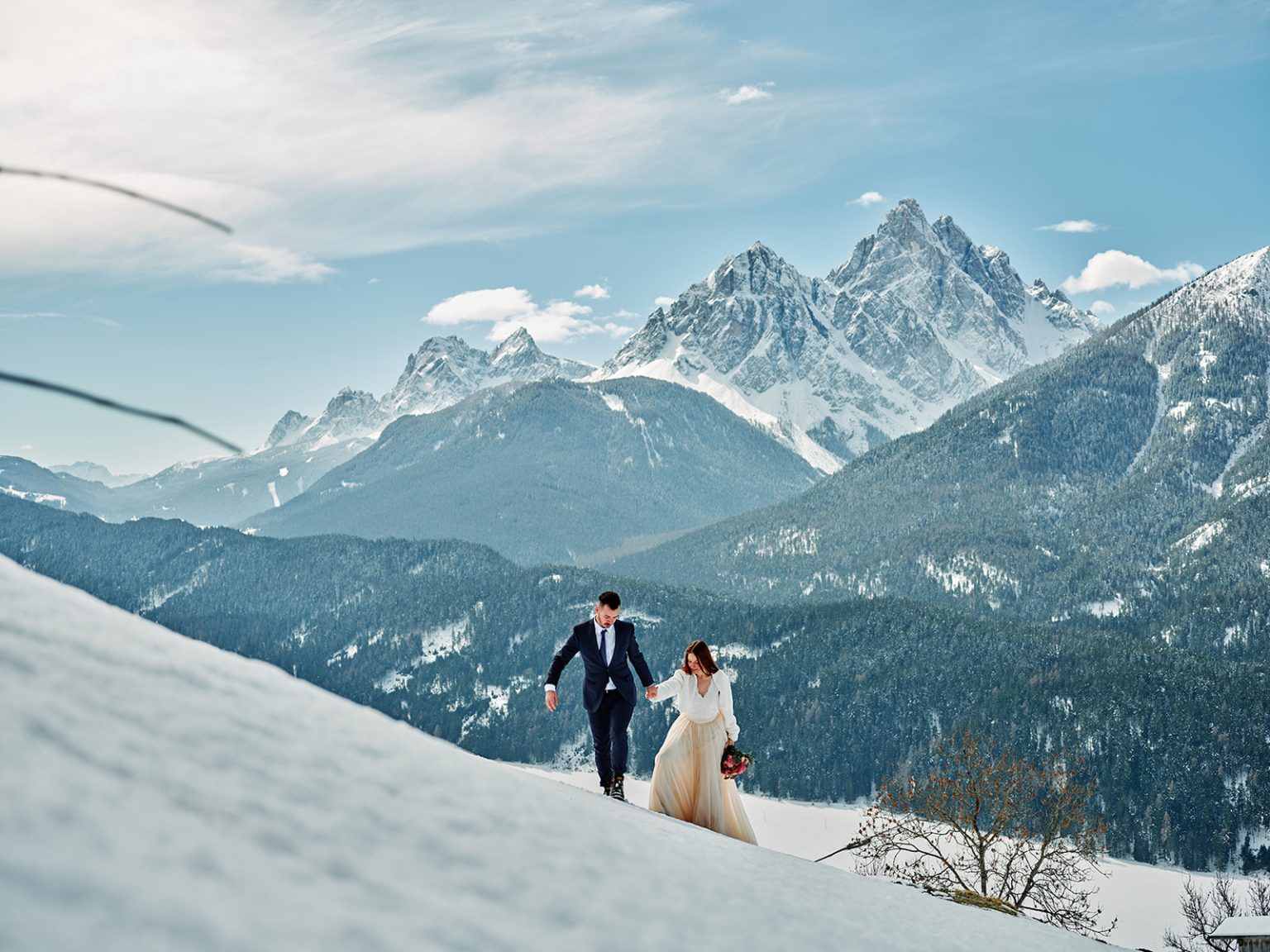 Kristina and Cristian walking the snowfields of Passo Giau, a winter elopement