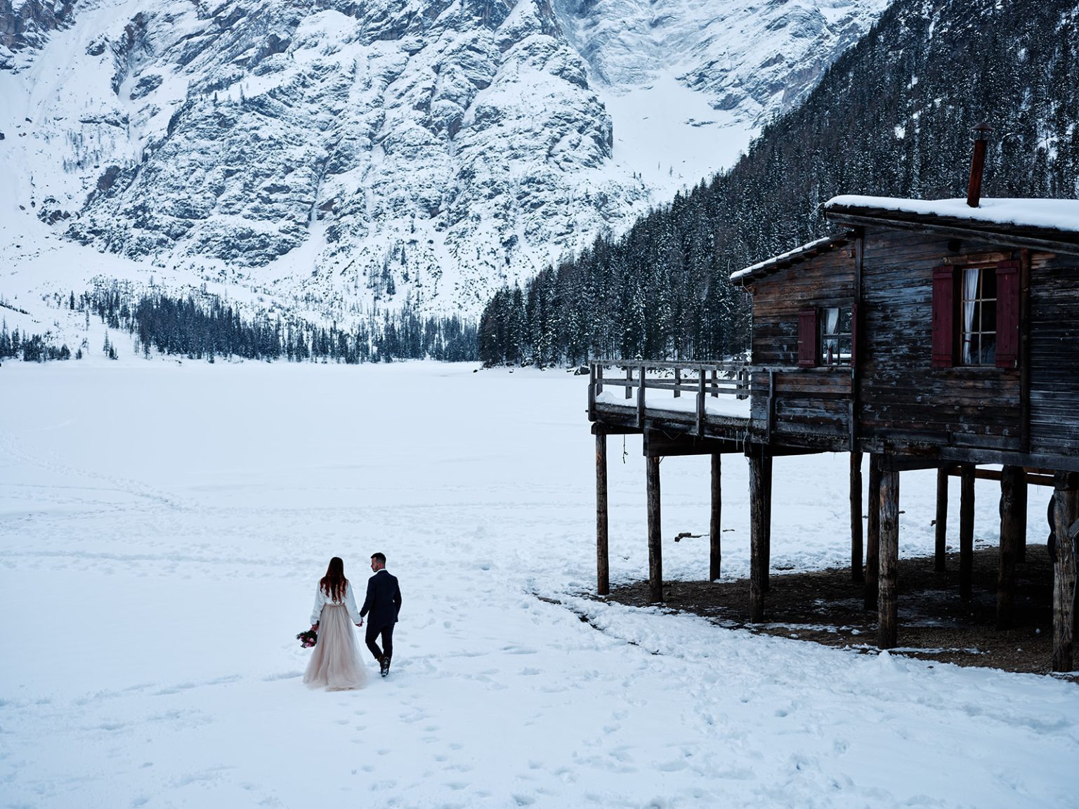 The Lago di Braies boathouse on the frozen lake, elope in the Dolomites in winter