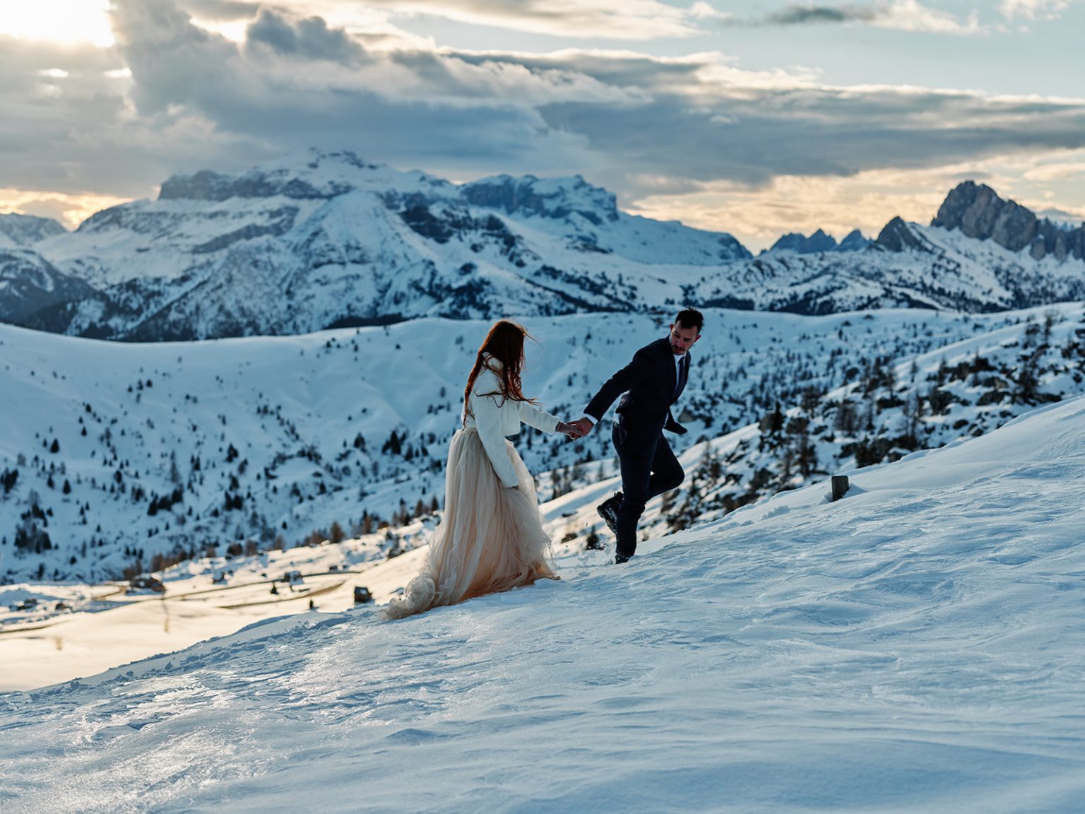 Last light on the peaks as the couple walk the snow, Dolomites winter elopement