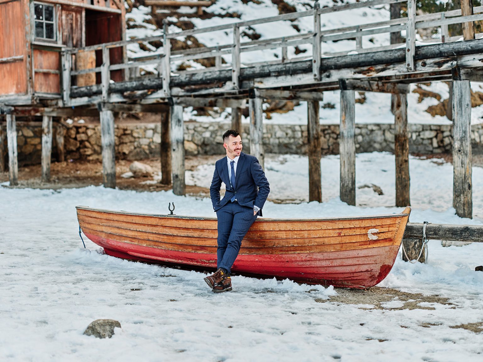 Cristian on the red boats by the Braies boathouse, the Dolomites in winter