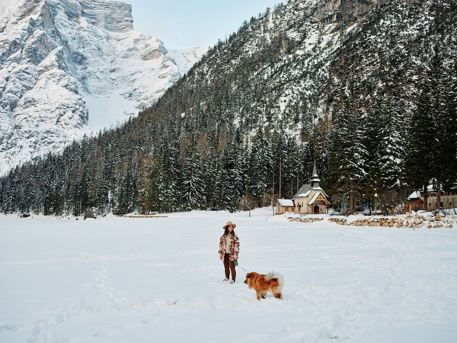 Walking the snowy shore of Lago di Braies with a dog, Dolomites winter elopement