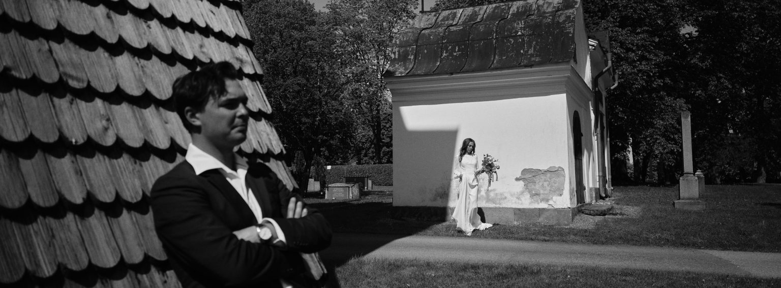 Groom seated in a Söderhamn park with white pavilions