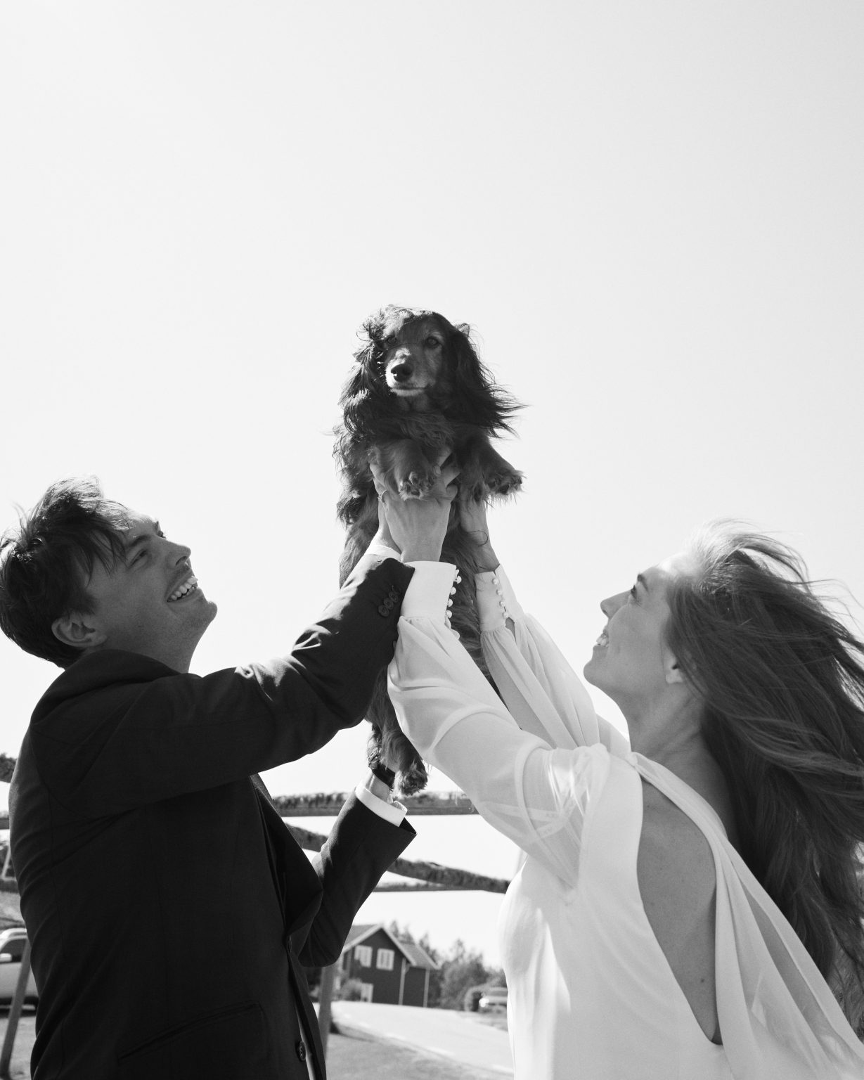 The couple lifting their spaniel on the elopement day near Skärså