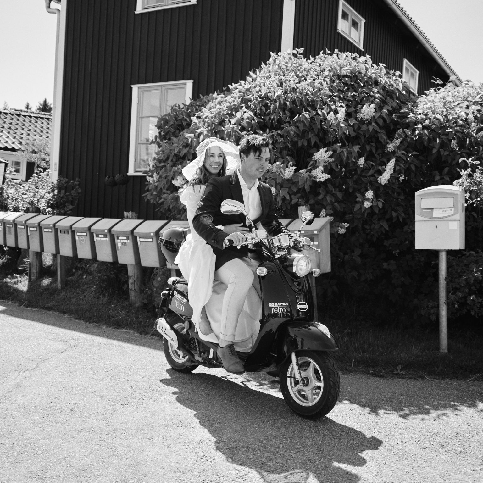 Elin and Joakim on a vintage moped by a flowering bush near Skärså