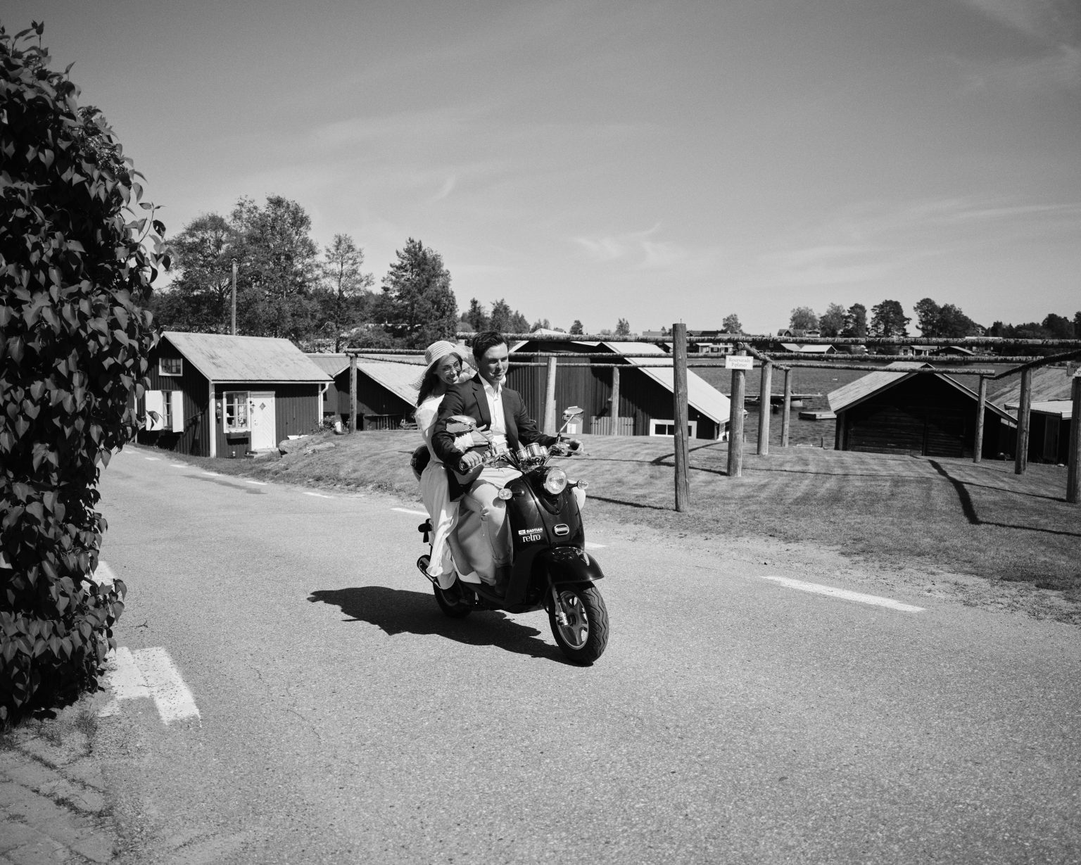 Elin and Joakim riding a moped through a coastal village near Skärså