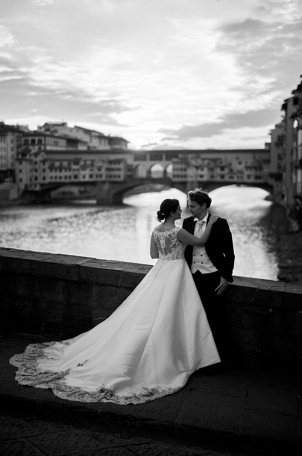 Bride and groom embrace on a bridge over the Arno at sunrise