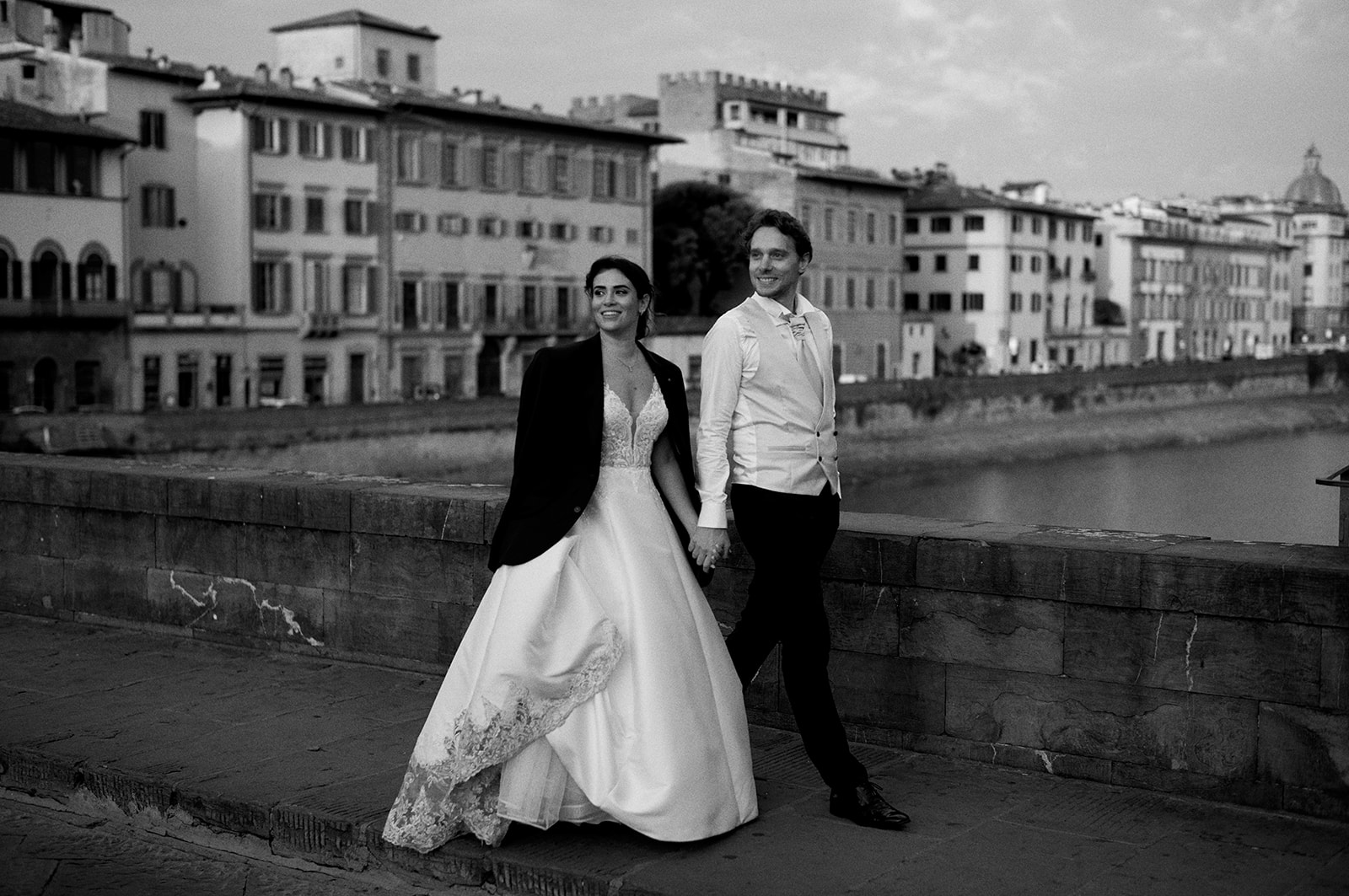 Bride and groom by the river wall in Florence at sunrise