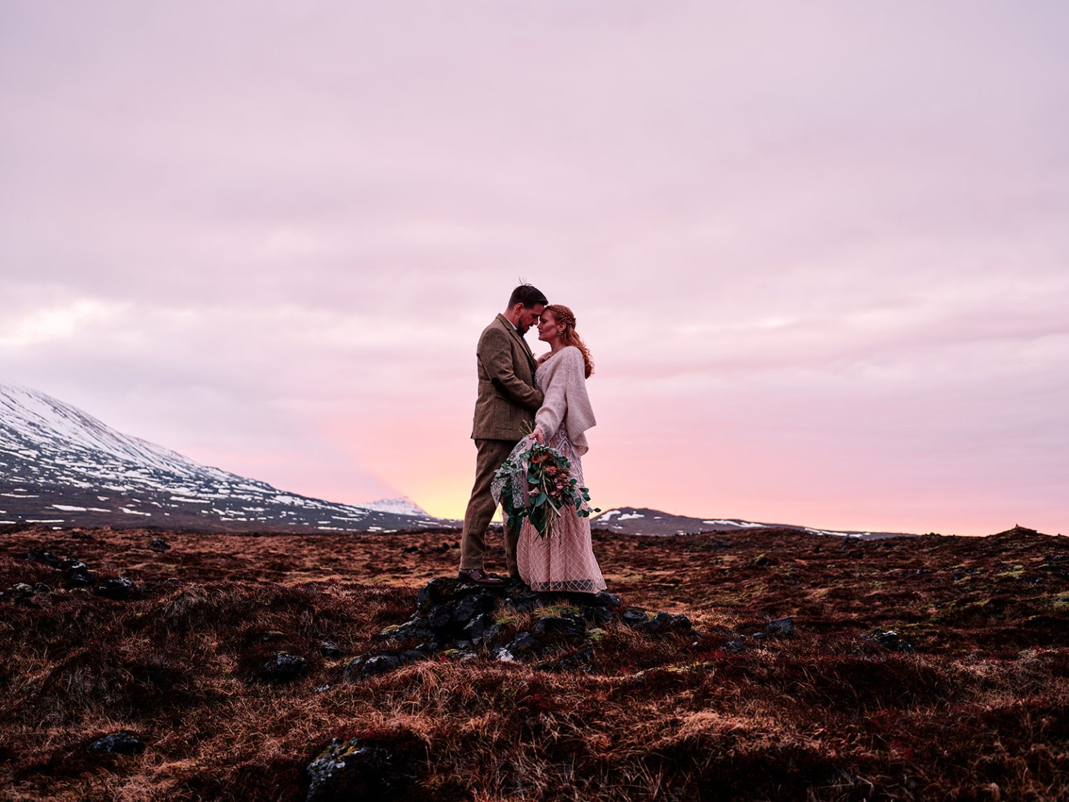 Halldóra and Örn embracing at pink dawn, a Hótel Búðir elopement