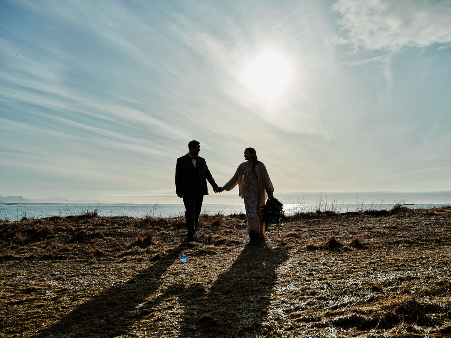 The couple holding hands in the sunburst, a Hótel Búðir elopement