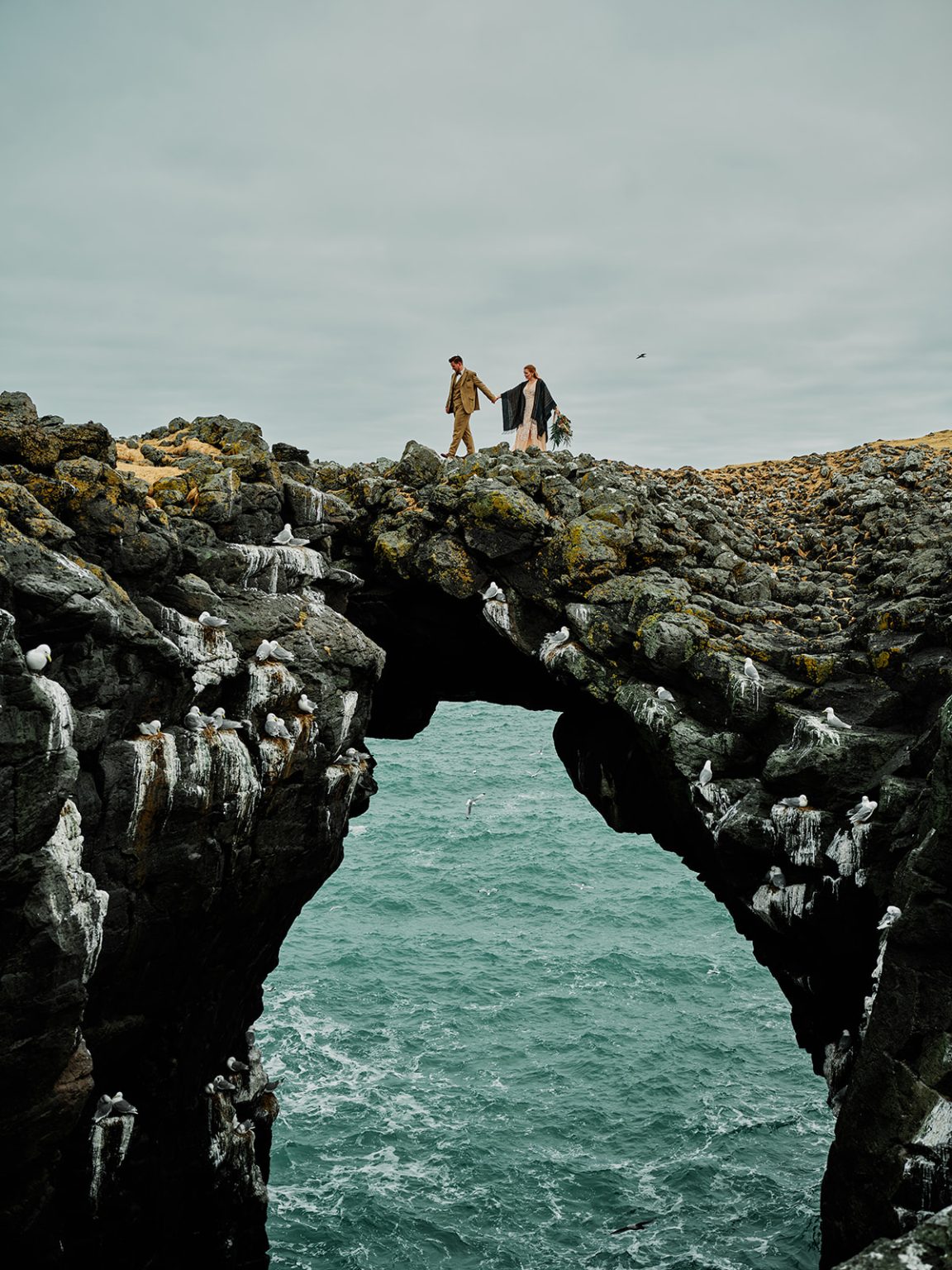 The couple by the Arnarstapi arch, a Hótel Búðir elopement
