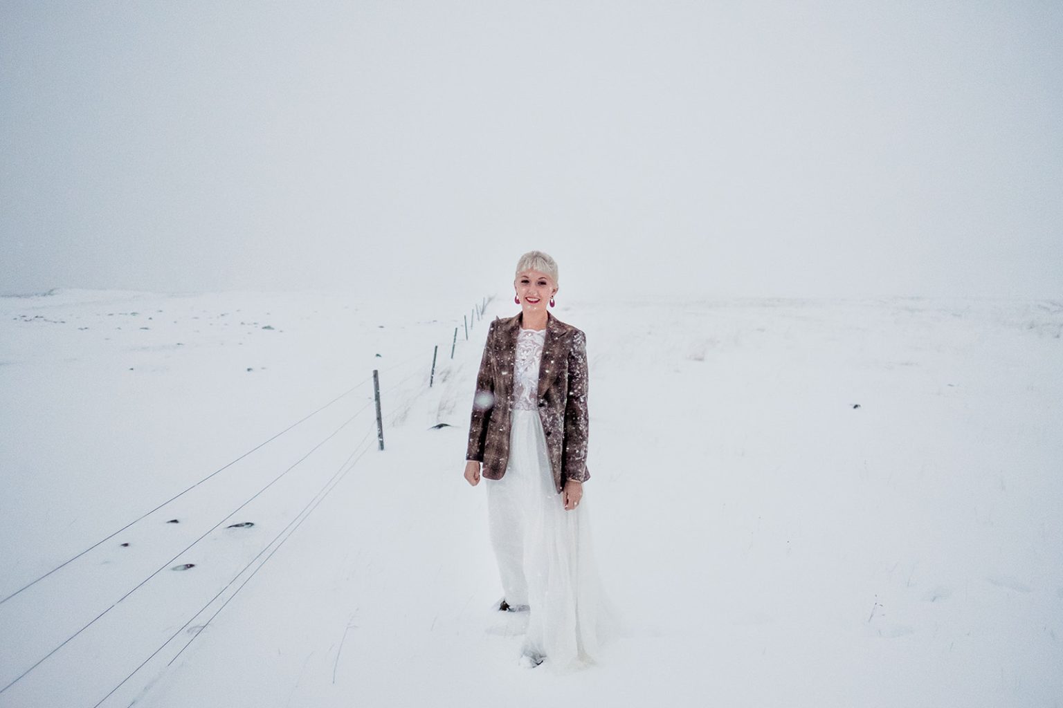 Bride and groom small against a white Icelandic snowfield in winter