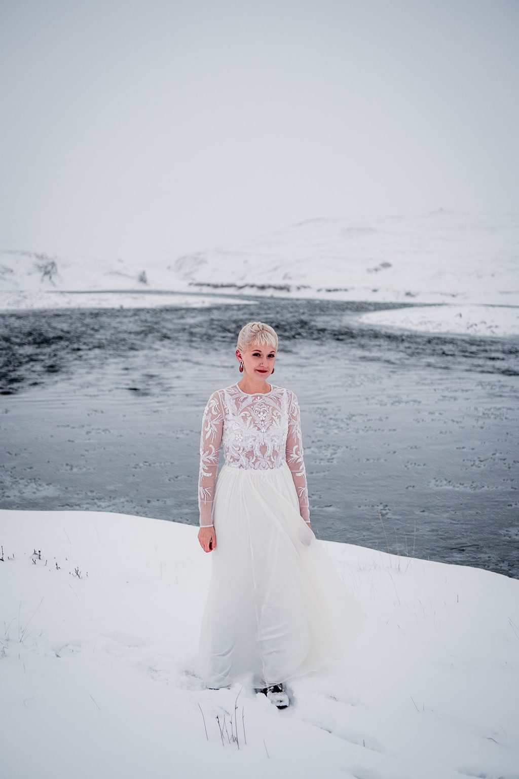 Bride walking through the snow beside the river