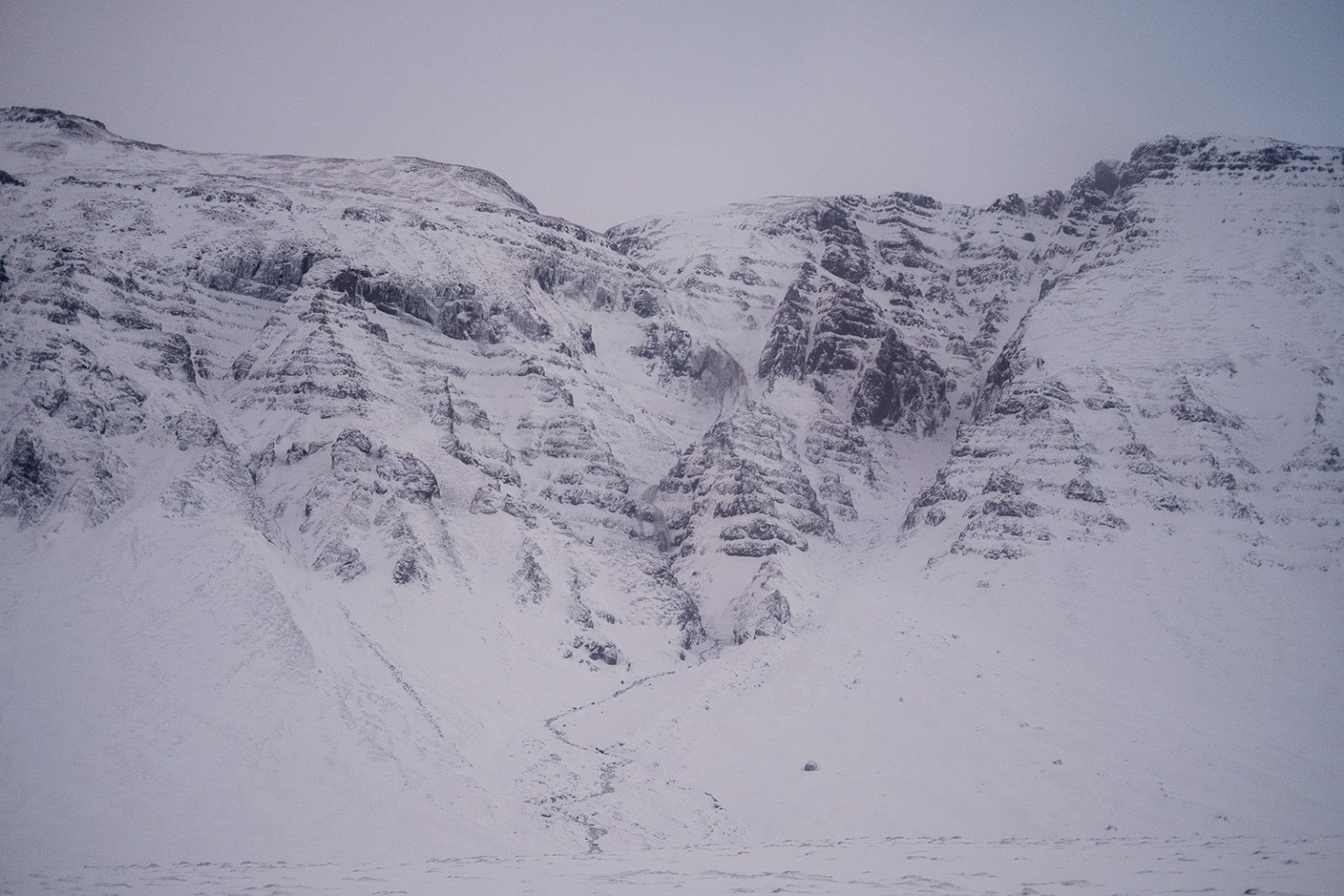 Couple as small figures beneath a snowy Icelandic mountain