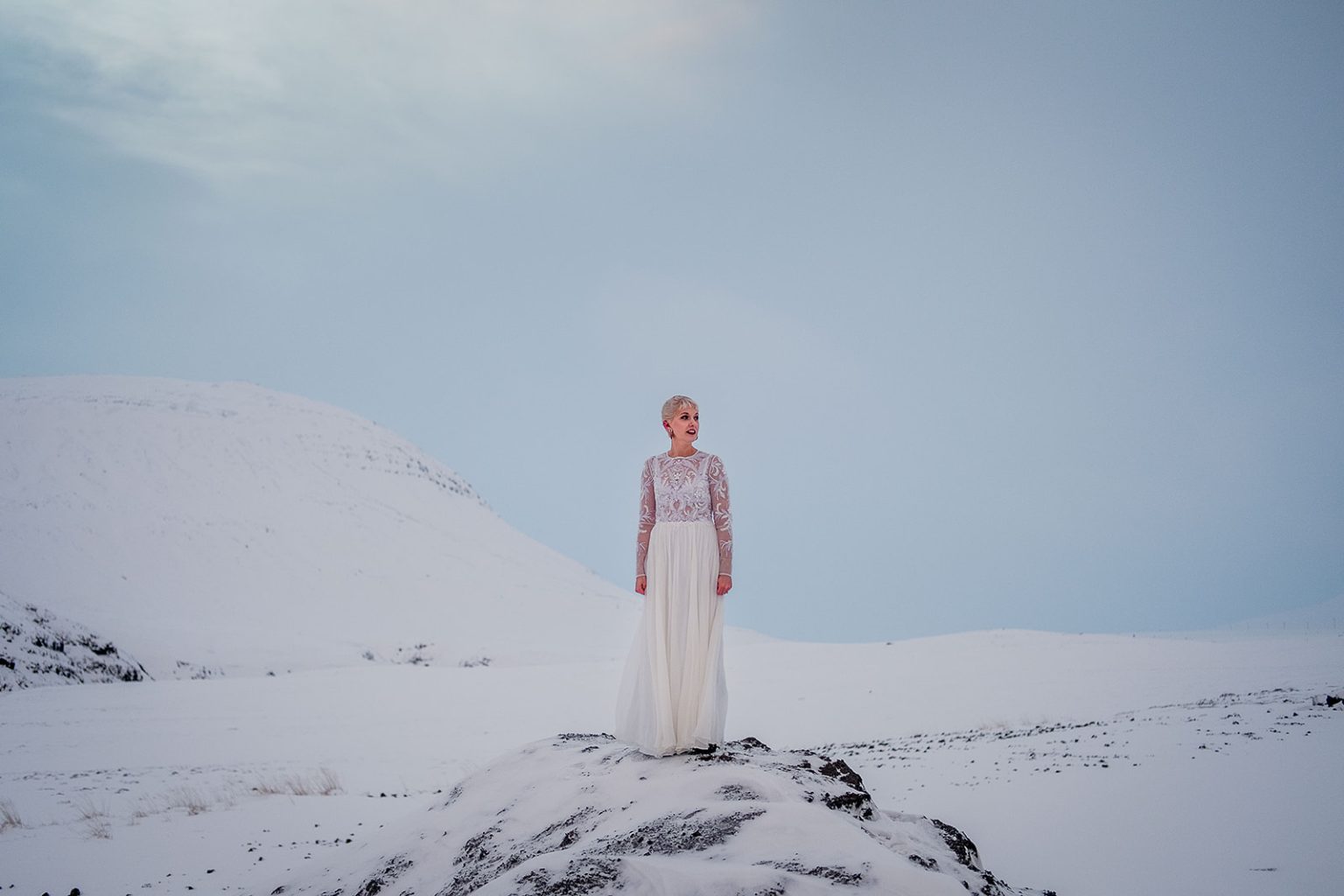 Bride and groom on a snowy ridge above Hvalfjörður