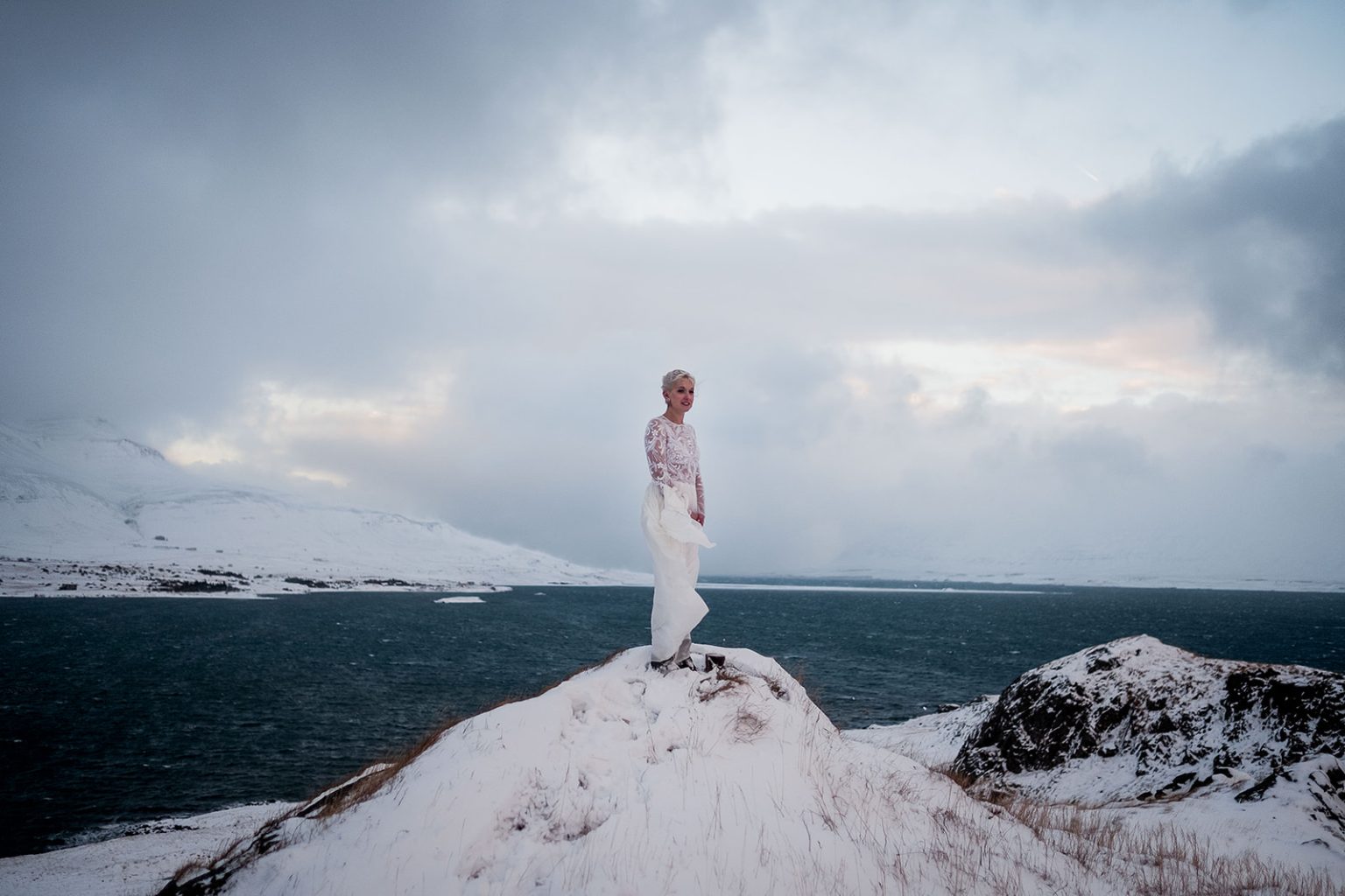 Couple standing high above Hvalfjörður in the snow