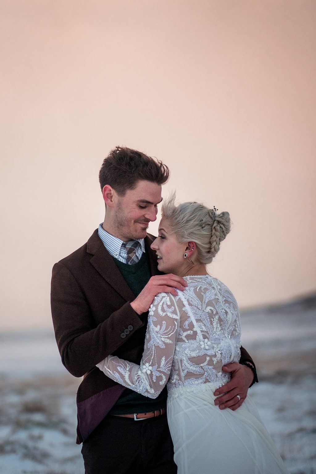 Bride and groom close in the pink evening light