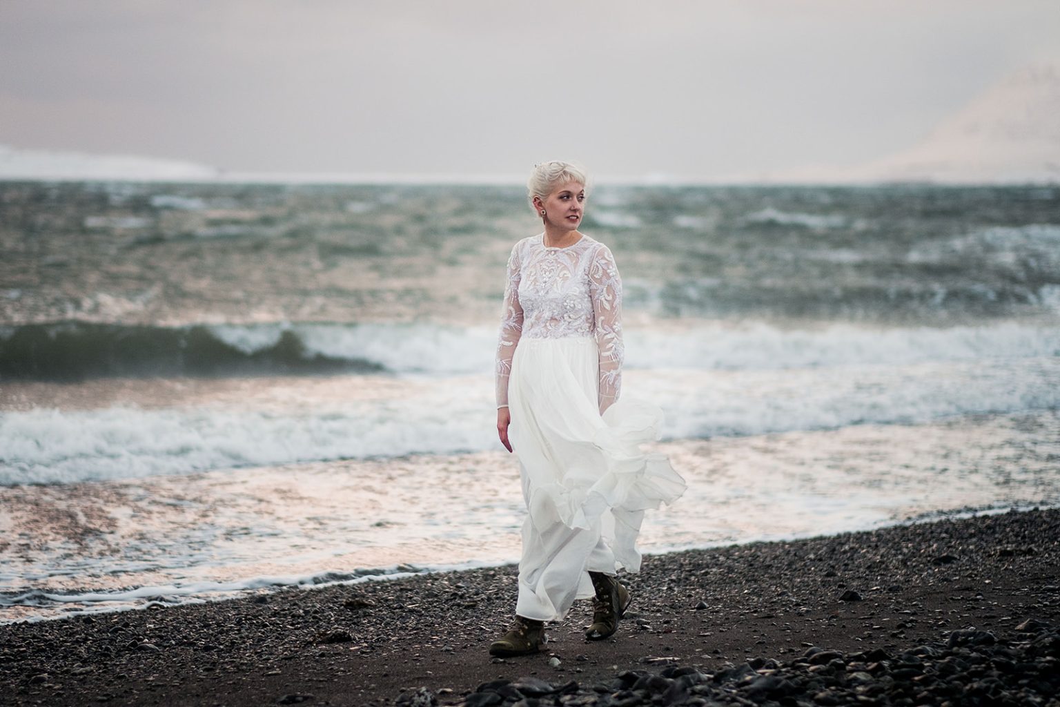 Bride on a dark beach as the winter waves break behind her