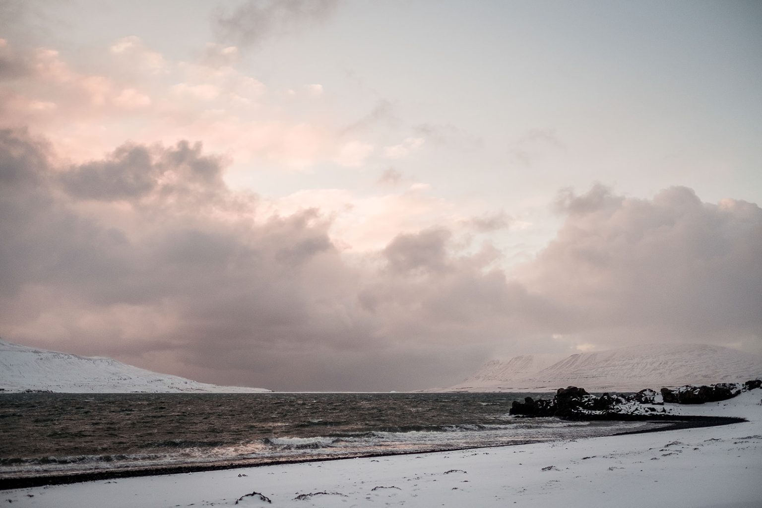 Couple by the winter sea on a black Icelandic beach