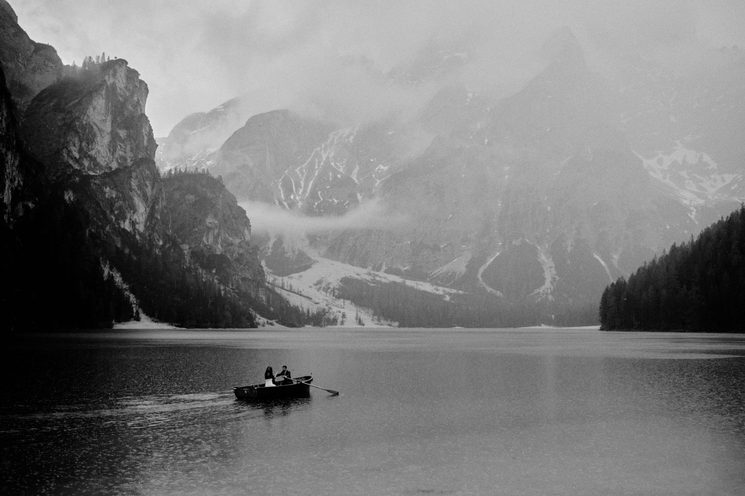 A single boat on Lago di Braies in the mist, black and white