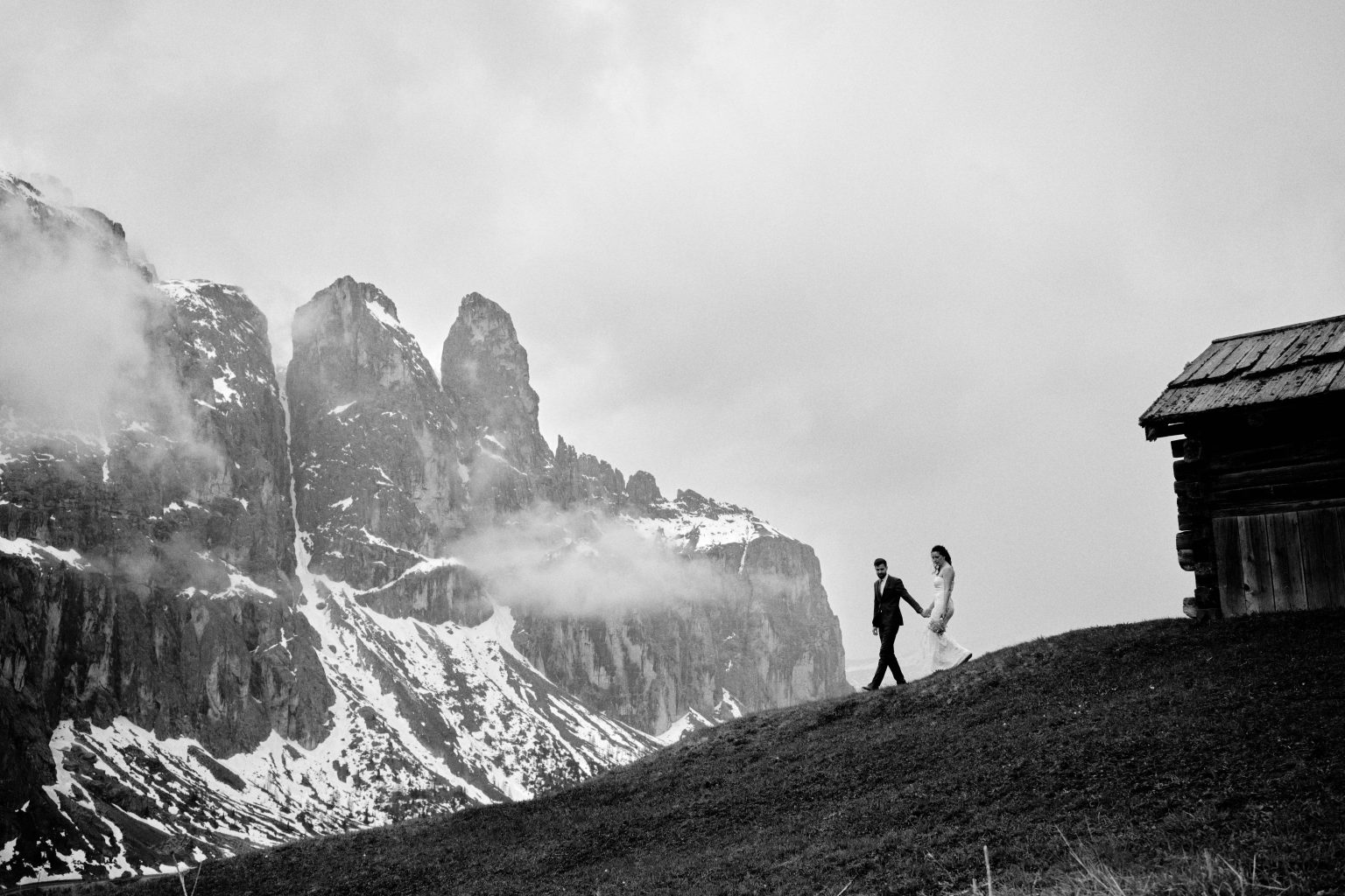 Simona and Marius walking a mountain ridge in the mist, Dolomites elopement