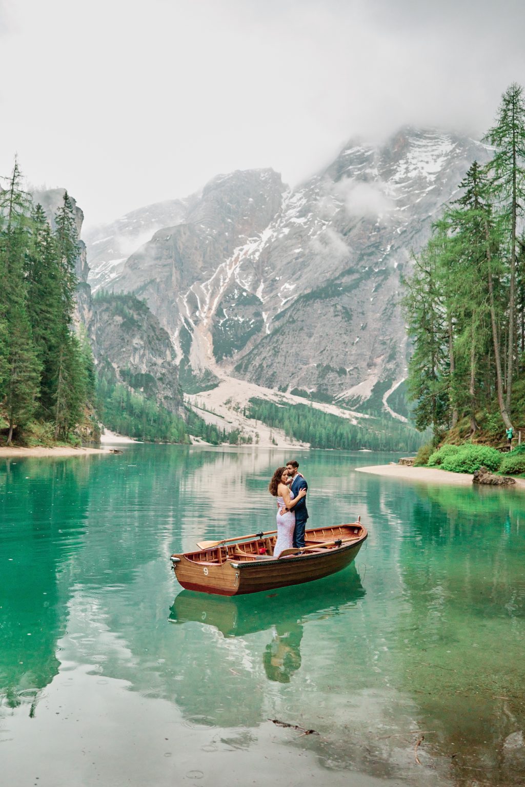 Couple small against the emerald water of Lago di Braies