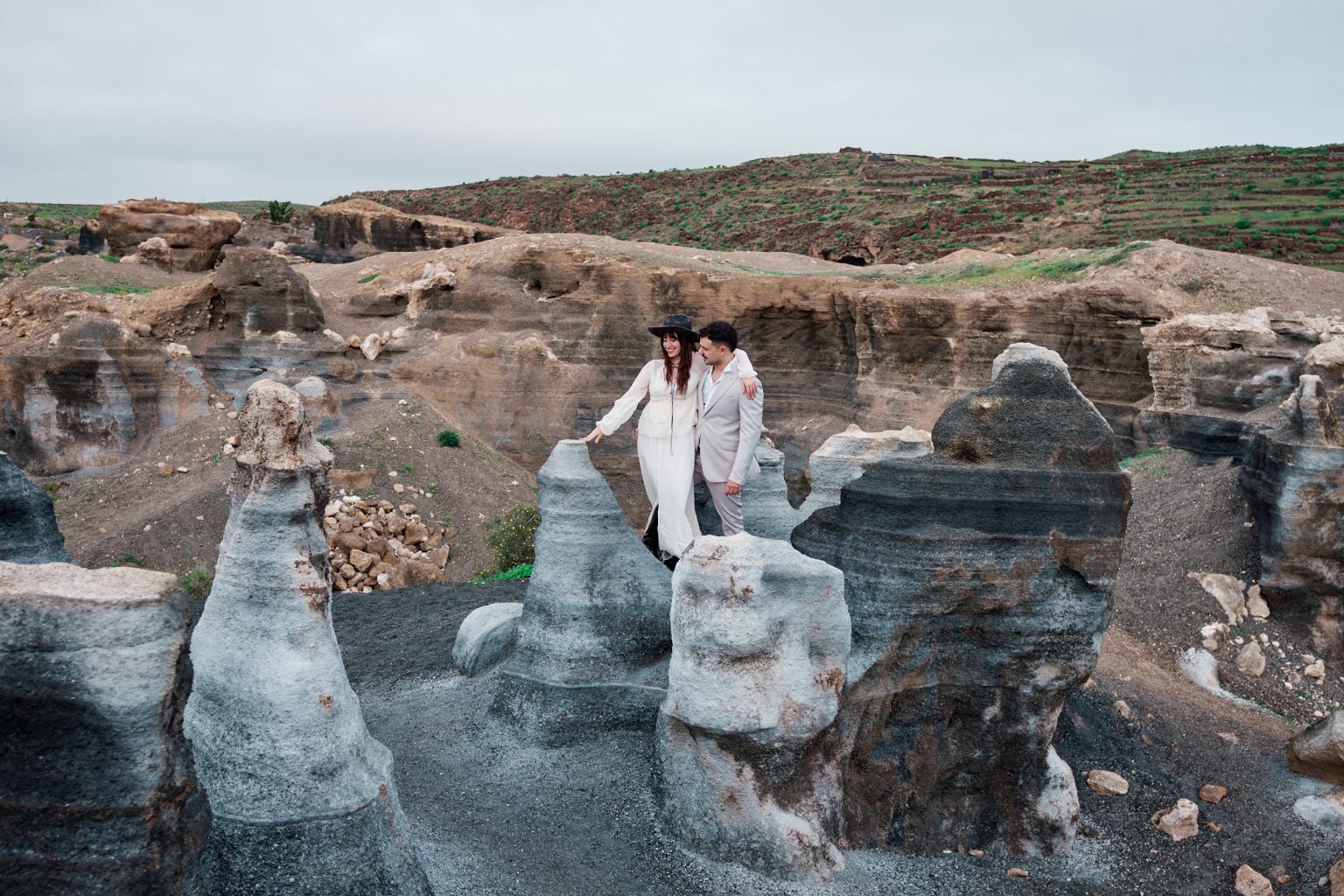 Couple on the grey rock coast with blue sea, Lanzarote