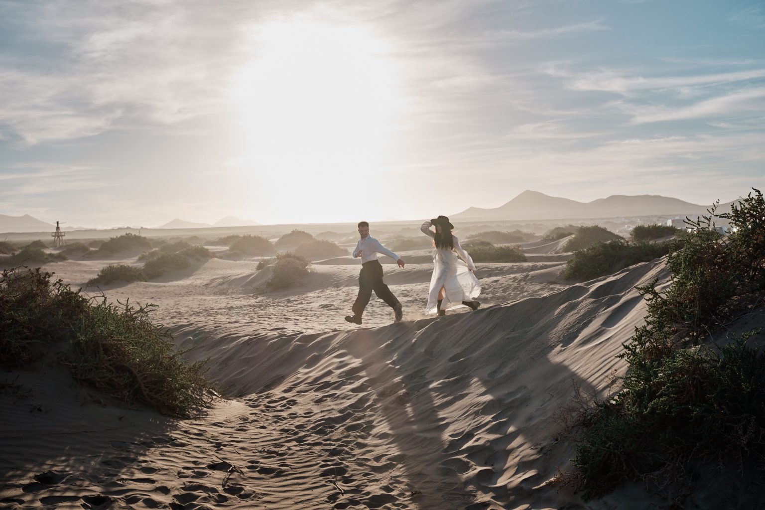Couple crossing the dunes in the wind, Lanzarote engagement photographer