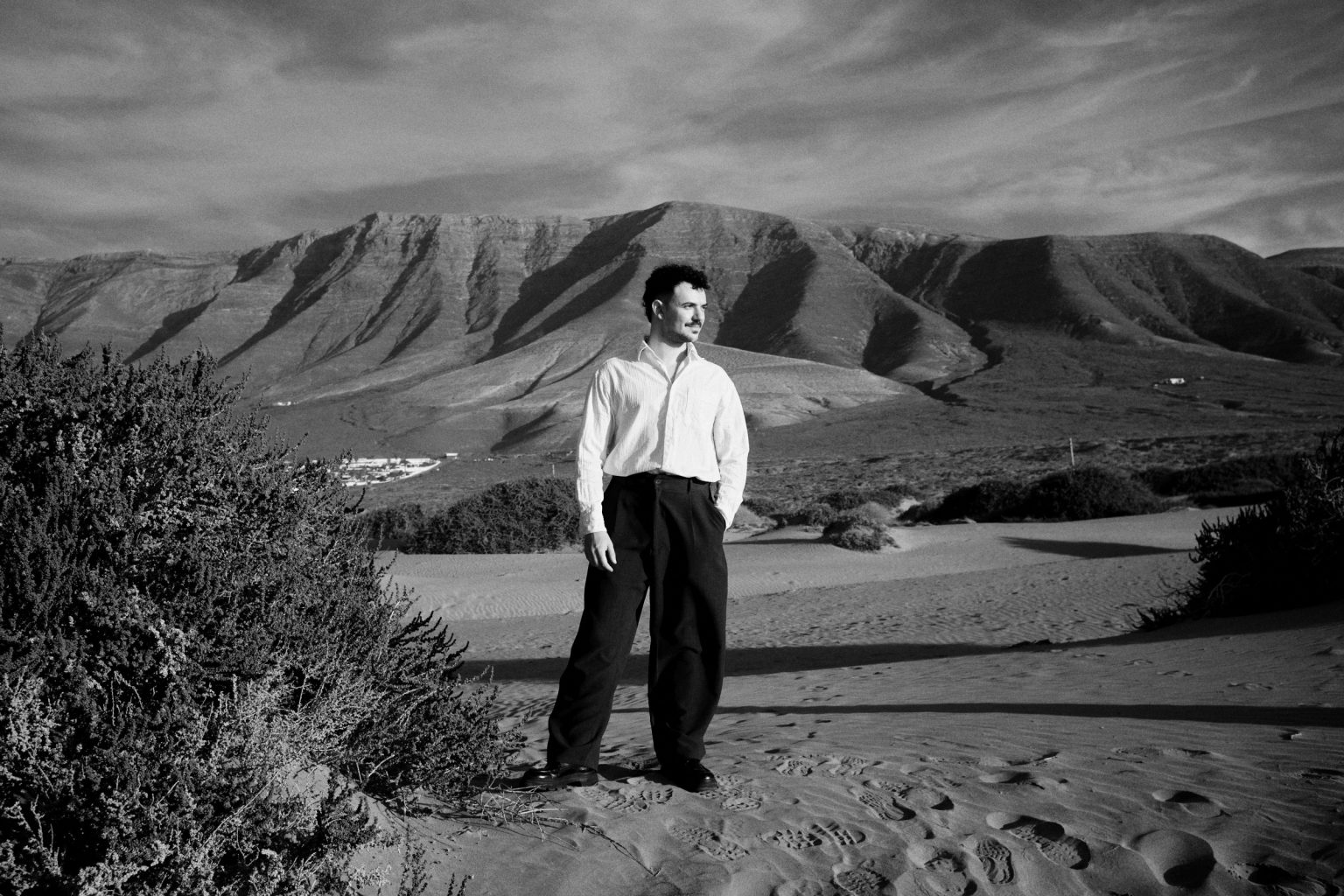 Groom sitting in the dunes, black and white, Lanzarote