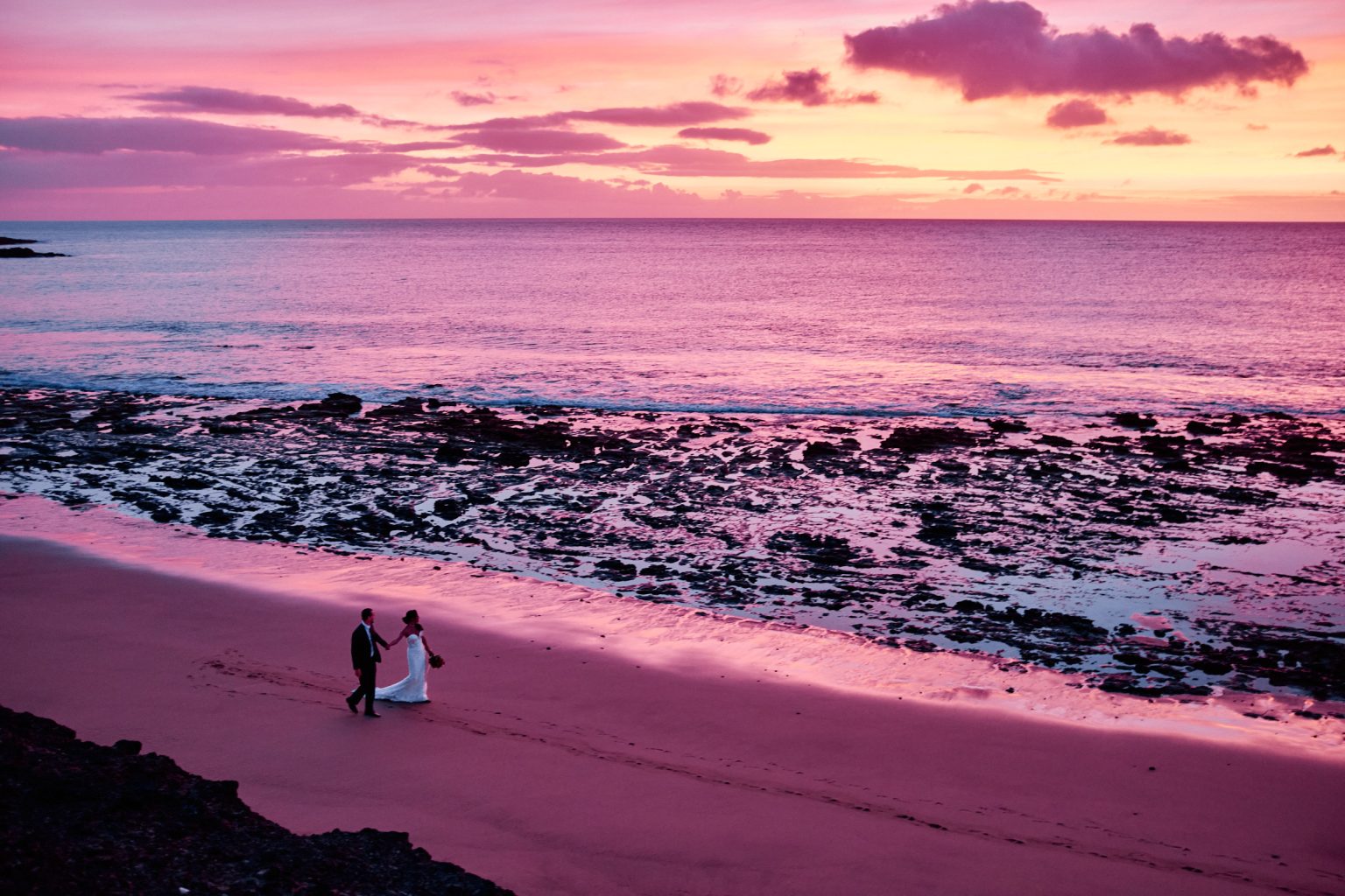 Couple walking a Lanzarote beach at first light